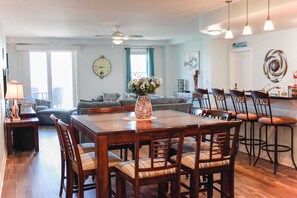 A dining area with a wooden table and chairs, a vase with flowers, and a clock on the wall.