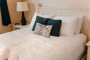 A neatly made bed with white bedding and multiple pillows, including a patterned one. - Sojourn Dune it Right Sleeps 8 Great Views (Virginia Beach)