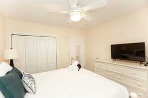 A hotel room with a bed, a television, a ceiling fan, and a dresser.