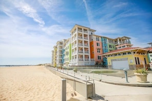 Een strandhotel met meerdere kleurrijke gebouwen, een zandstrand en een pier op de achtergrond.