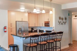 A modern kitchen with a central island, stainless steel appliances, and pendant lighting.
