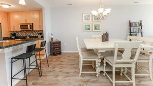 Een moderne keuken met een magnetron, een eettafel met stoelen en een kroonluchter.
