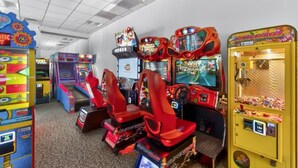 Een rij speelautomaten met racegames, waaronder een SuperCarts racegame, en een grijpmachine.
