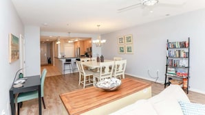 A modern living room with a dining area, a bookshelf, and a ceiling fan.