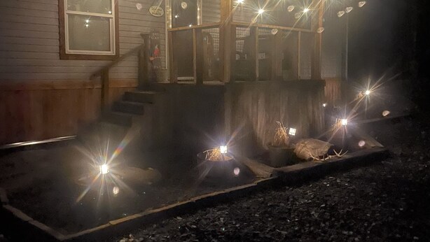 Een overdekt buitengebied met lichtjes en een vuurkorf.