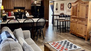 Een gezellige woonkamer met een bank, een salontafel en een eethoek met stoelen en een tafel.