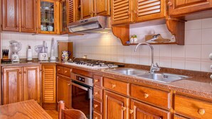 Una cocina con armarios de madera, estufa a gas, pileta y diversos electrodomésticos.