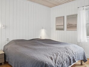 Un dormitorio con una cama grande, paredes blancas y dos cuadros en la pared.