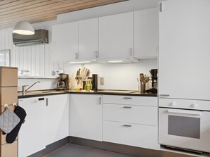 A modern kitchen with white cabinets, a stainless steel refrigerator, and a coffee maker.