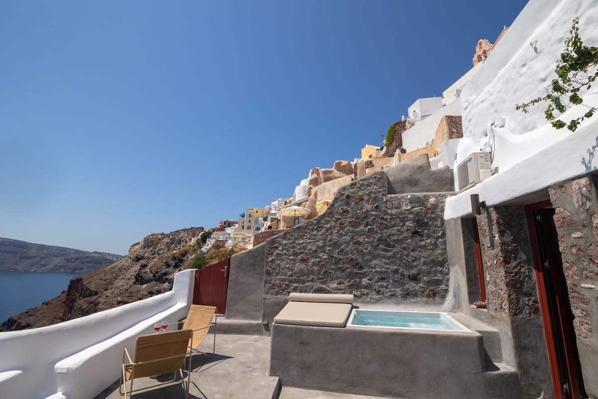 Una terraza en la azotea con un muro de piedra, una pequeña piscina y vista al mar.