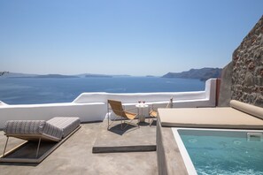 A rooftop terrace with a pool, lounge chairs, and a table with glasses. - Kyrkos Residency (Santorini)