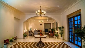 Un hall d’entrée spacieux, agrémenté d’un lustre, d’un coin salon et de grandes fenêtres.