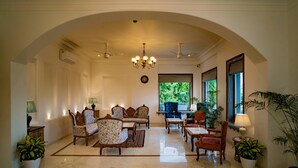 Un hall d’entrée spacieux, doté d’un haut plafond en arc, d’un mobilier élégant et de grandes fenêtres offrant une vue sur la verdure.