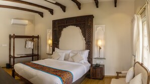 Une chambre à coucher de style traditionnel, avec un lit en bois, un banc, une table de chevet avec une lampe et une armoire.