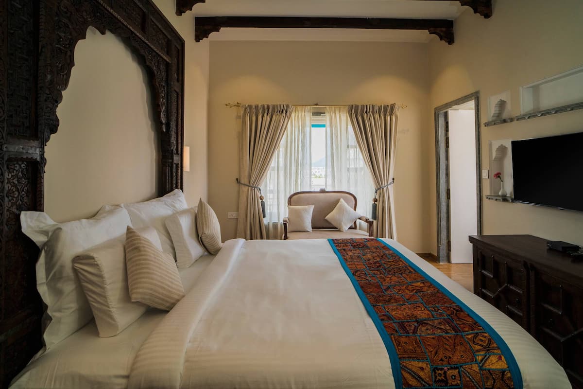 Een hotelkamer met een groot bed, een houten hoofdeinde, een televisie en een stoel.