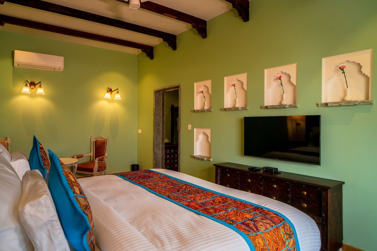 Een hotelkamer met een groot bed, een televisie en een kaptafel.