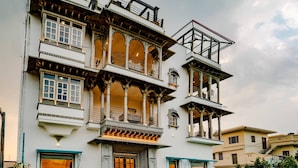 Un immeuble à plusieurs étages doté de balcons, une entrée principale avec des marches et une cour intérieure carrelée.