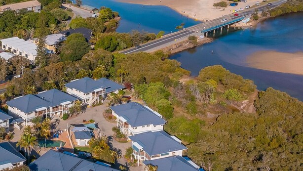 Vista aérea de una zona residencial costera con casas, una playa y un puente.