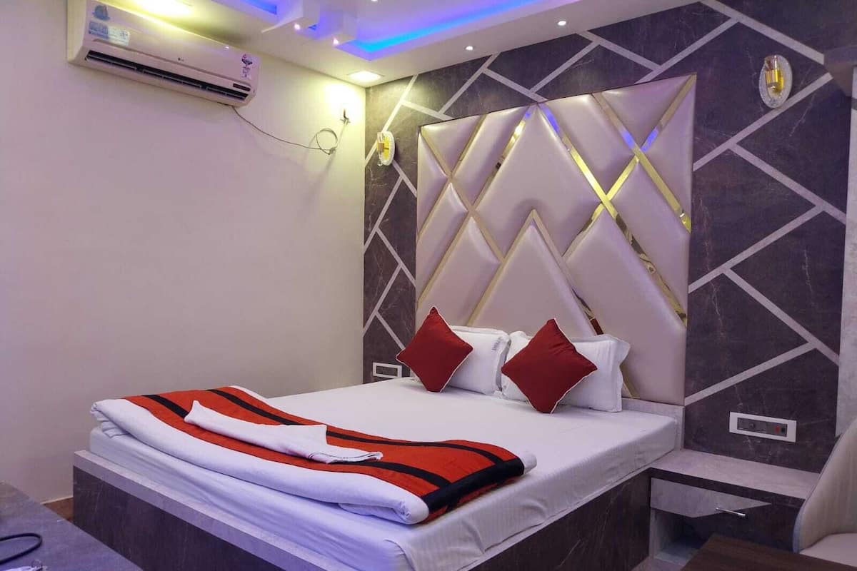 A modern hotel room with a bed, bedside table, and a wall-mounted air conditioner.