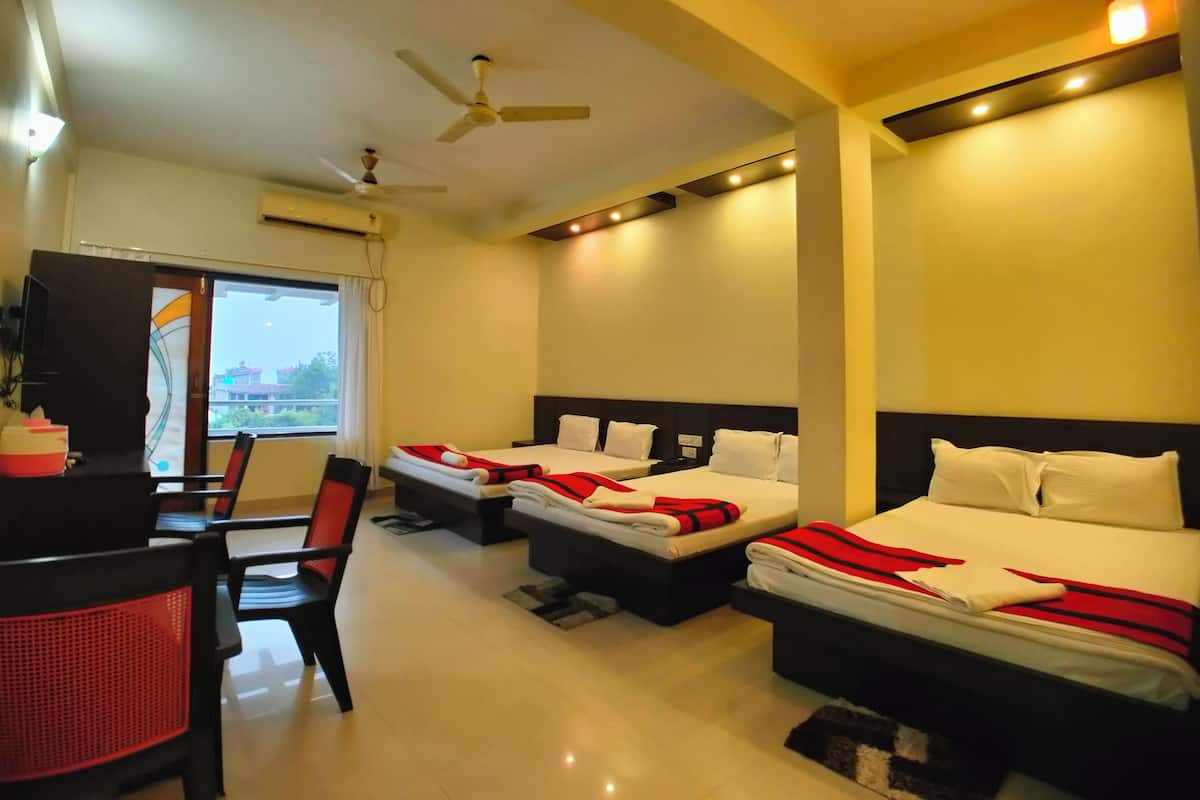 A hotel room with two beds, a desk, chairs, and a ceiling fan.