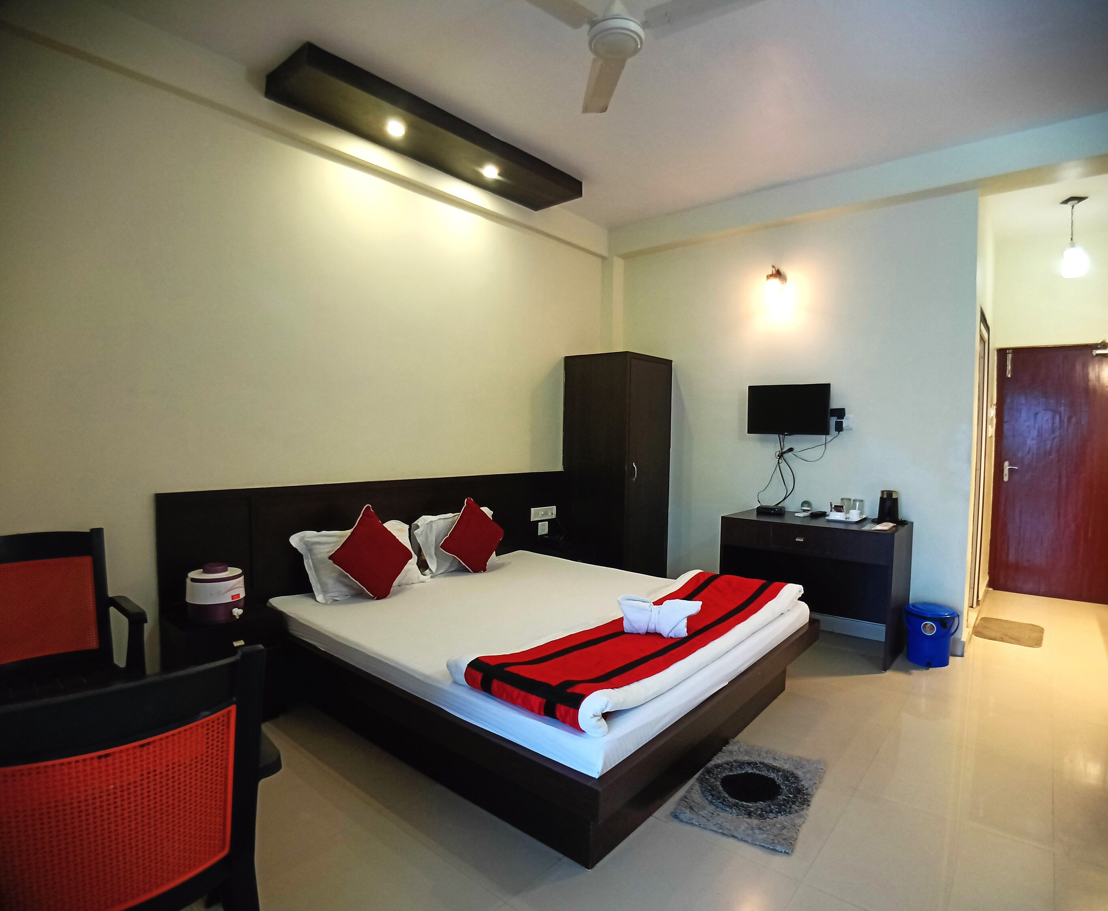 A hotel room with a bed, a desk, a chair, a television, and a wardrobe.