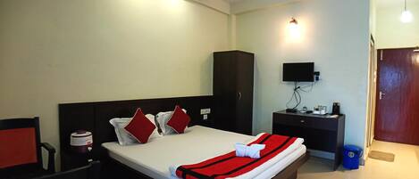 A hotel room with a bed, a desk, a chair, a television, and a wardrobe.