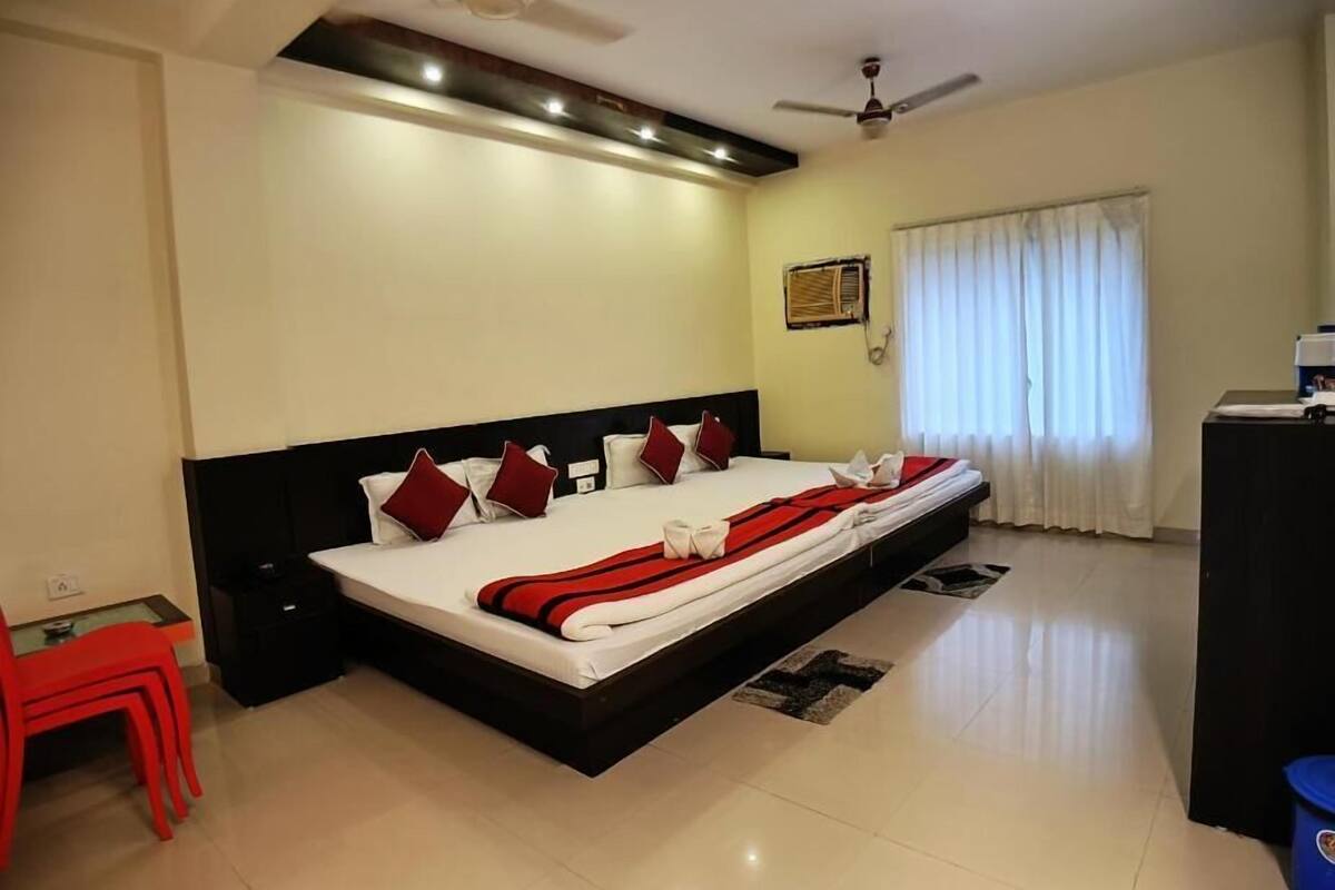 A bedroom with a large bed, two ceiling fans, a window with curtains, and a small desk.