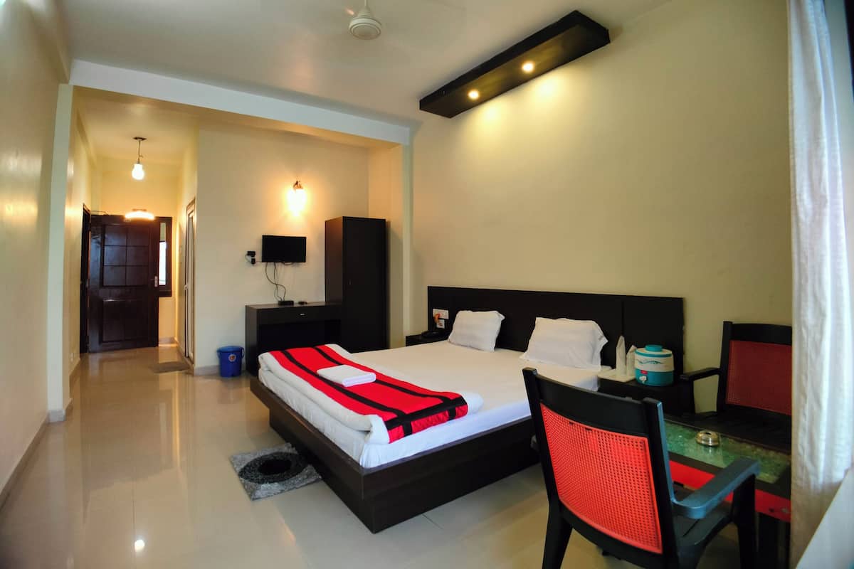 A hotel room with a bed, a desk, a chair, a television, and a ceiling fan.