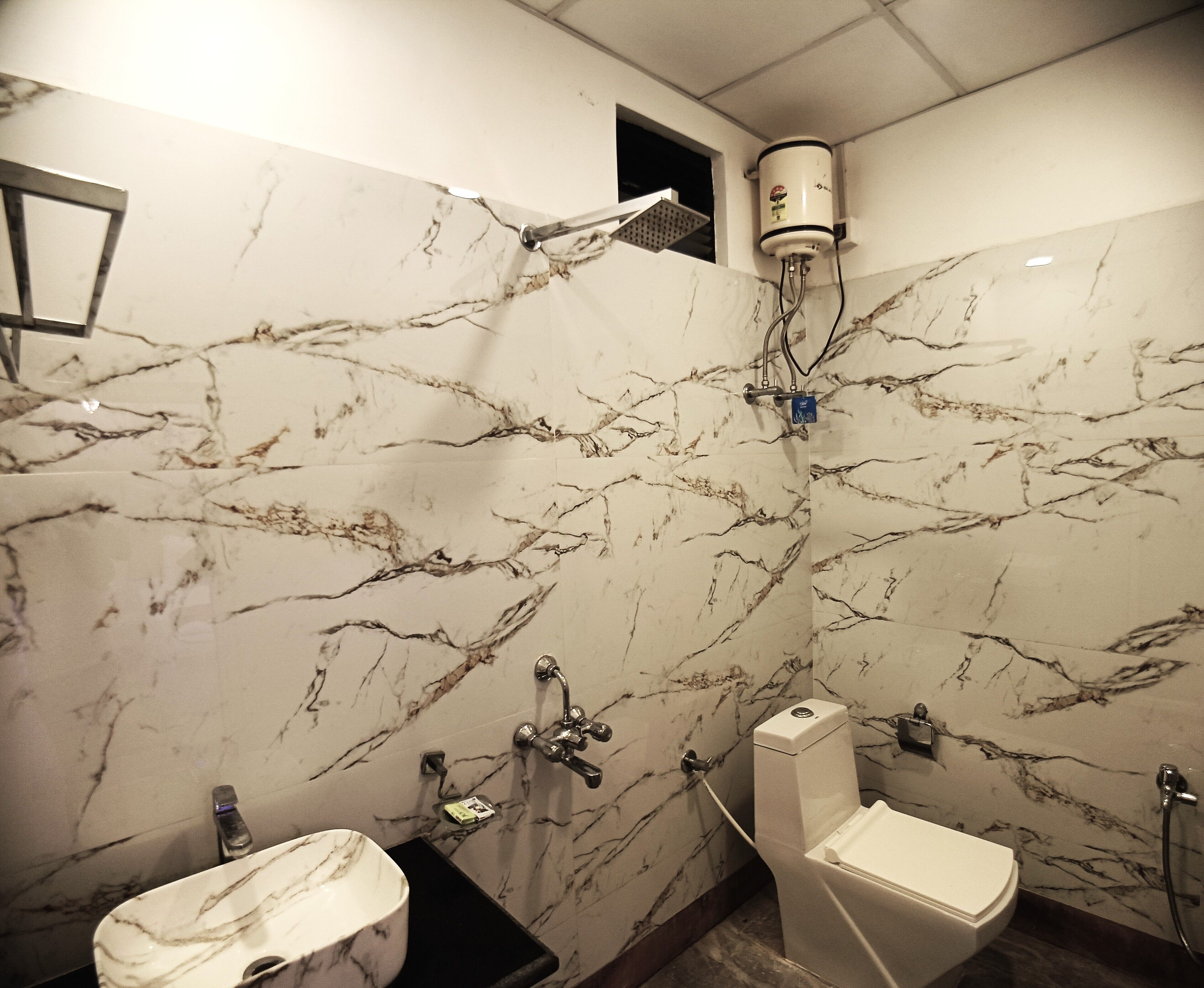 Un baño con paredes de mármol, un inodoro, un lavabo y una ducha.