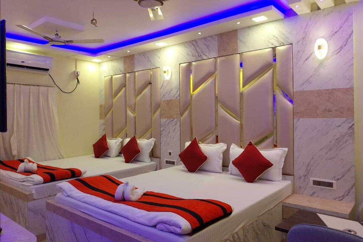 A hotel room with two beds, marble walls, ceiling fans, and ambient lighting.