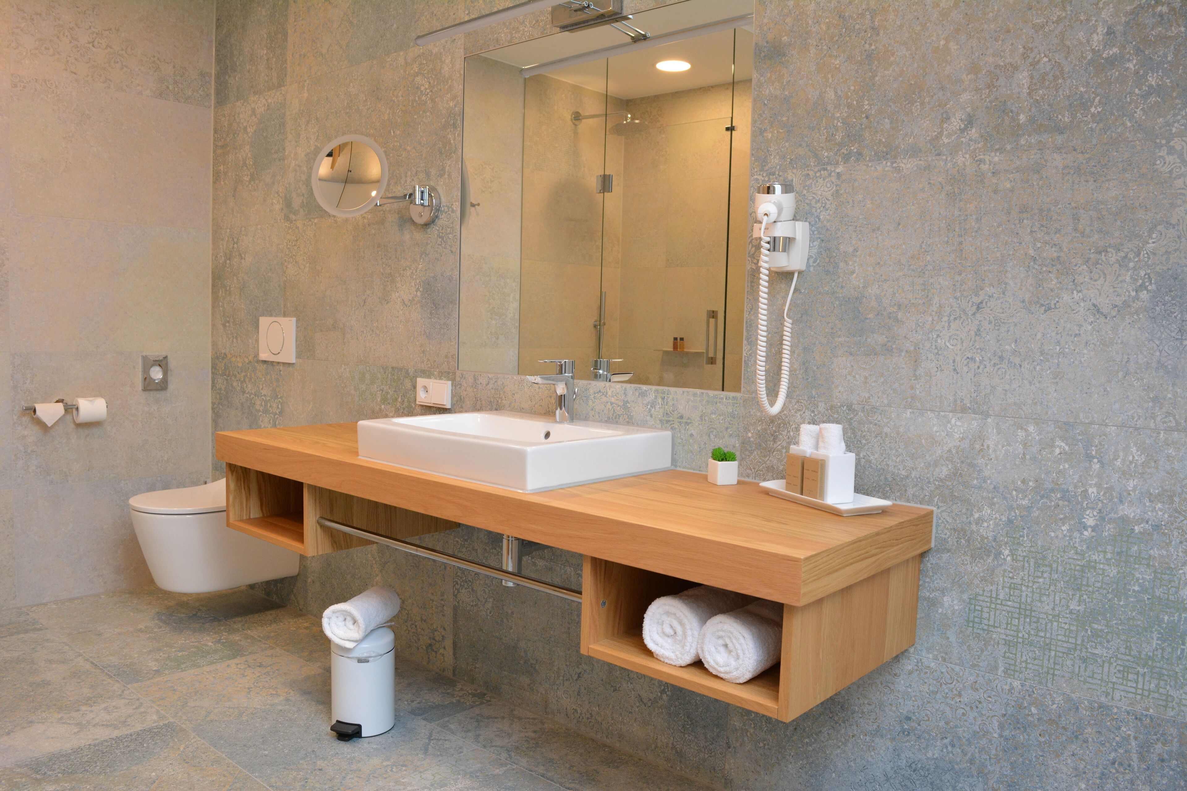 Un baño moderno con un espejo grande, un lavabo y un inodoro.