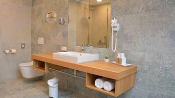 Un baño moderno con un espejo grande, un lavabo y un inodoro.