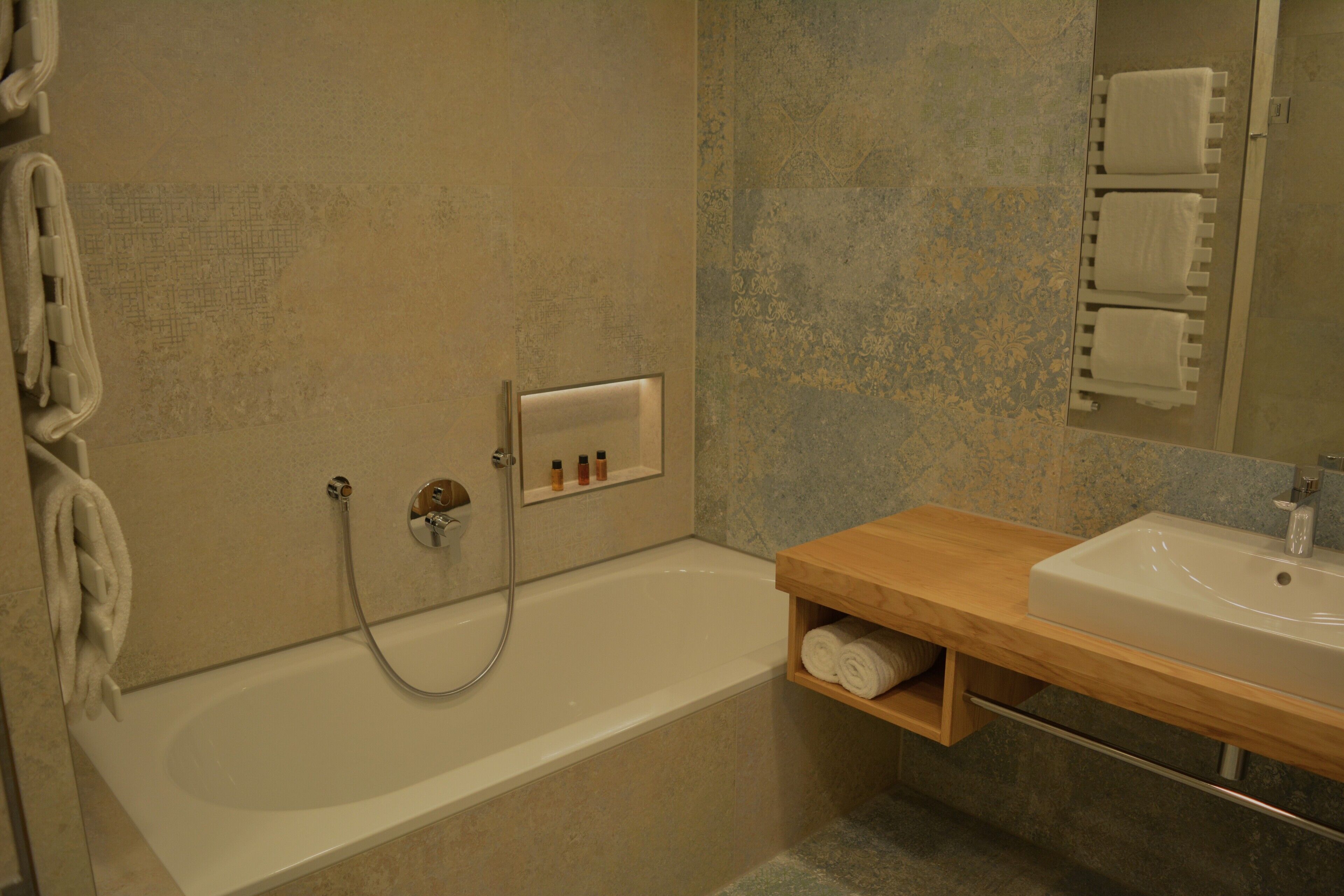 A bathroom with a bathtub, a wooden vanity, a towel rack, and a mirror.