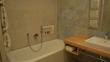 Une salle de bain avec une baignoire, un meuble-lavabo en bois, un porte-serviettes et un miroir.