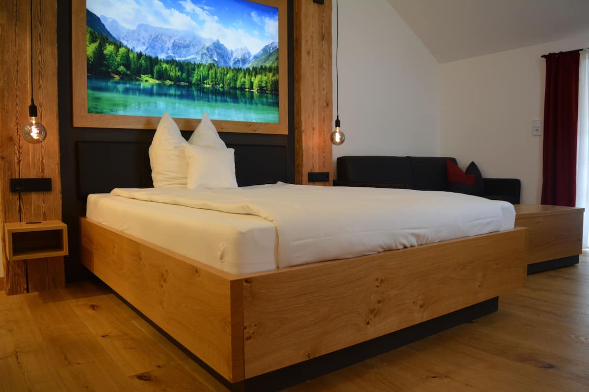 Une chambre à coucher moderne avec un lit en bois, un grand téléviseur fixé au mur et une table de chevet en bois.