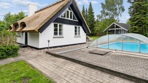 A house with a thatched roof, a swimming pool with a glass enclosure, and a paved patio. - "Emanuela" - 800m from the sea by Interhome (Gilleleje)