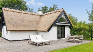 A modern house with a thatched roof, a patio with lounge chairs, and a dining table. - "Emanuela" - 800m from the sea by Interhome (Gilleleje)