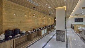 Een moderne hotel lobby met een lange receptiebalie, houten lambrisering en een marmeren vloer.