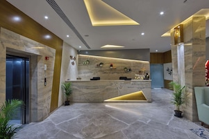 Un área de recepción moderna con un mostrador de mármol, una recepción y un espacio de estar con una silla.