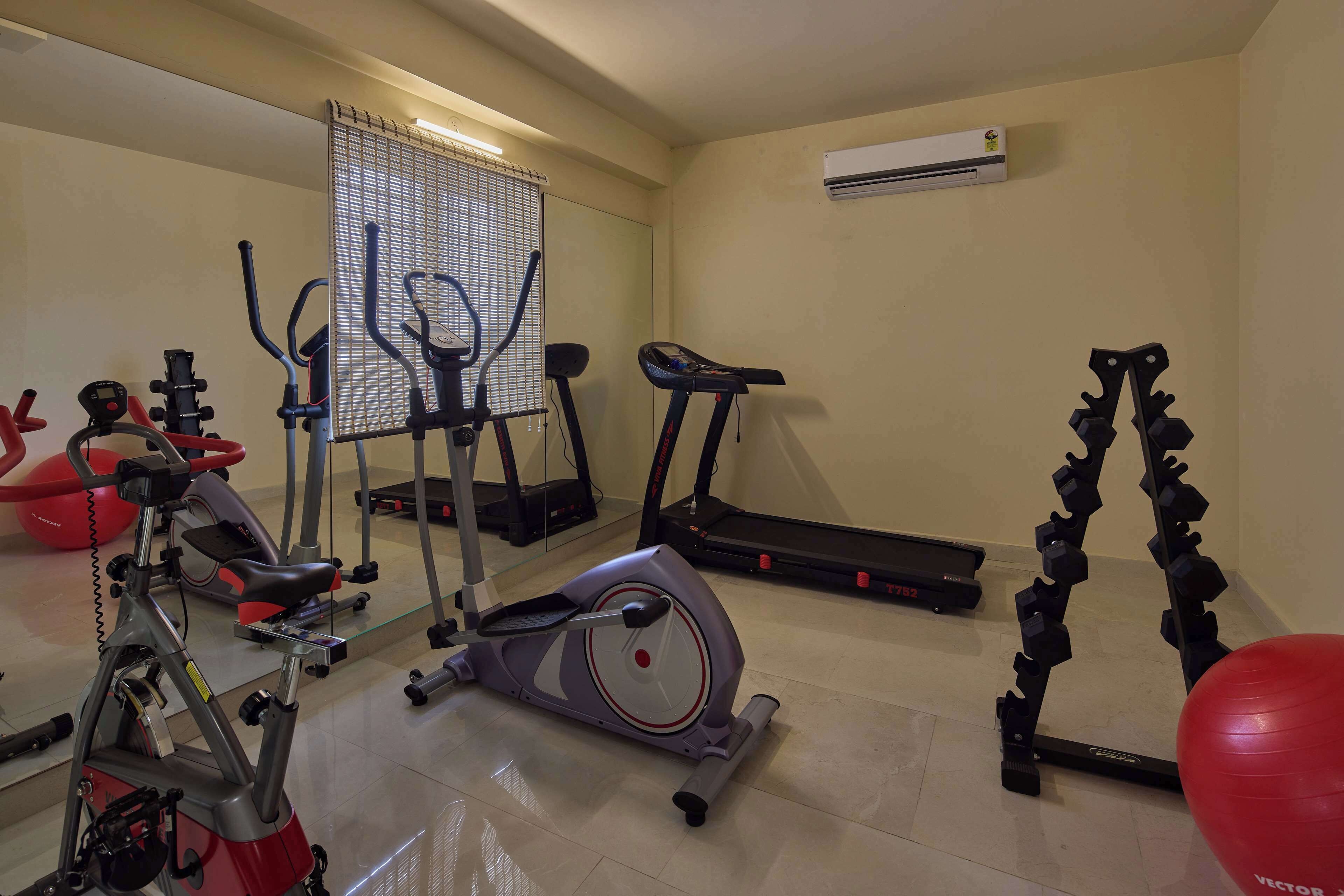 A home gym with various exercise equipment including a stationary bike, elliptical, treadmill, and resistance bands.