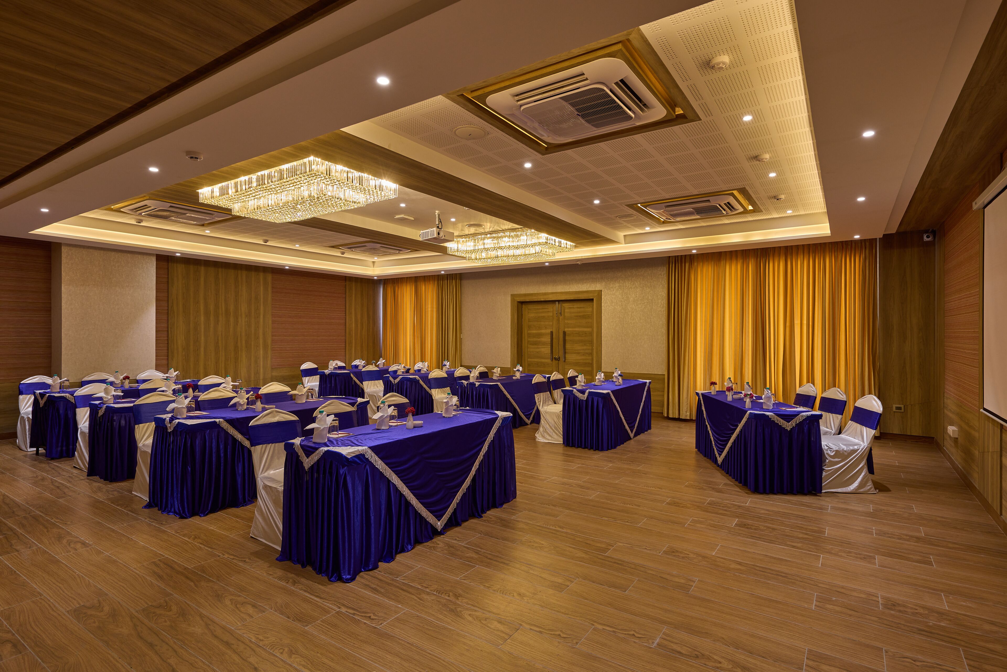 A conference room with multiple tables and chairs, equipped with microphones and nameplates, and a large chandelier.