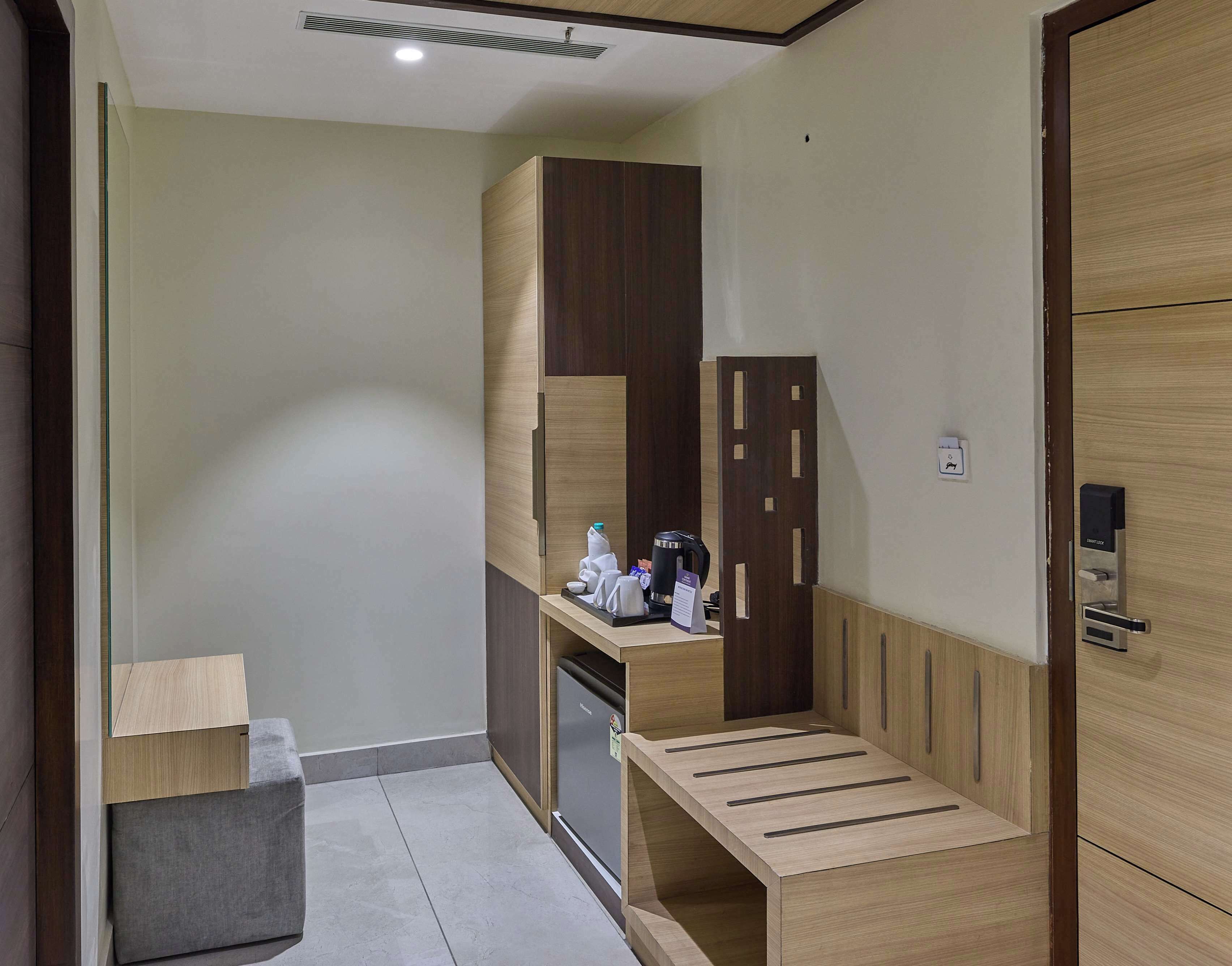 A compact room with a kitchenette, a small seating area, and a wardrobe.
