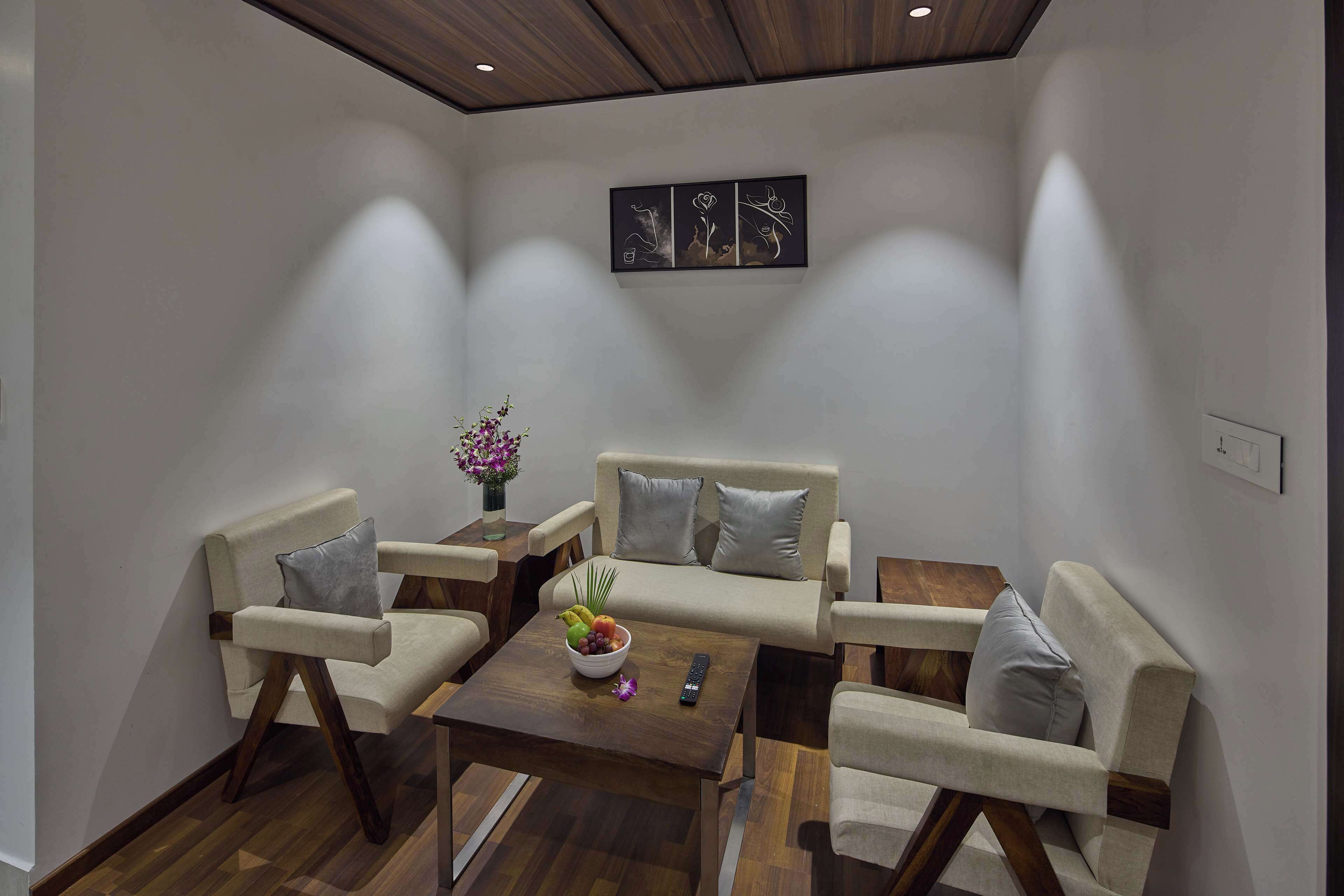 A modern living room with a sofa, armchairs, a coffee table, and a wall-mounted artwork.