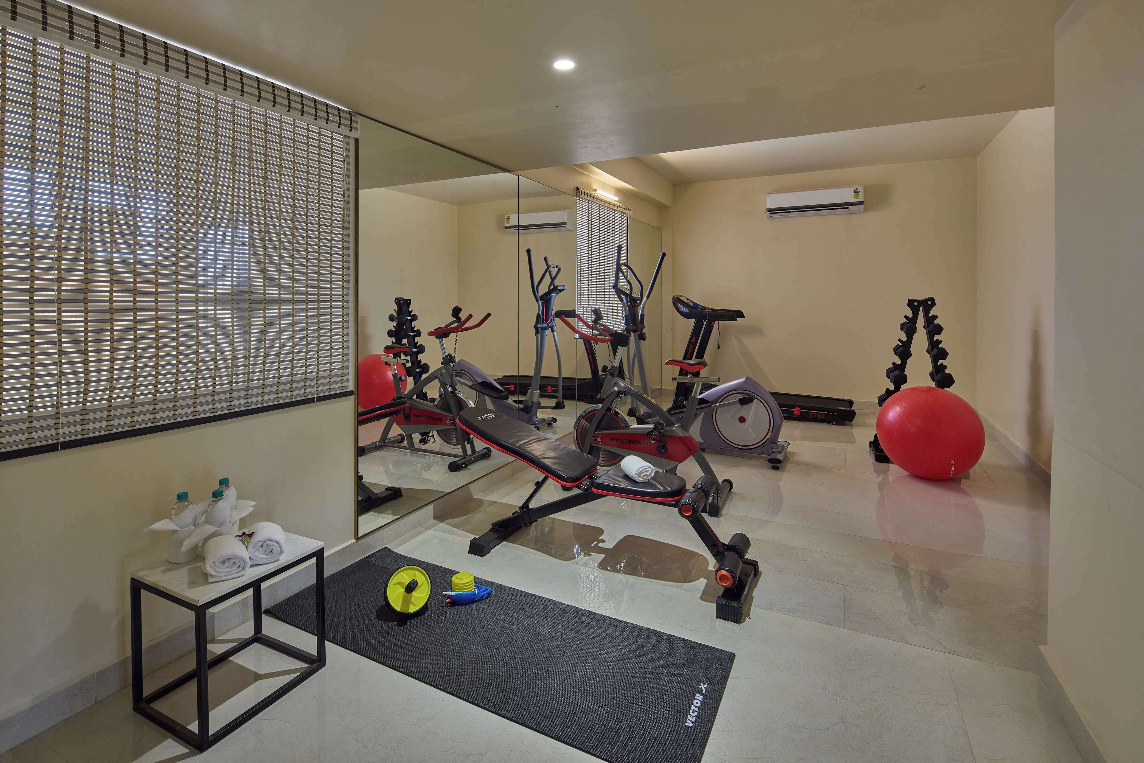 Un gimnasio con equipo de ejercicio, una banca, una colchoneta y una pequeña mesa con toallas y botellas de agua.