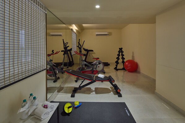 Un gimnasio con equipo de ejercicio, un espejo y una colchoneta para yoga.