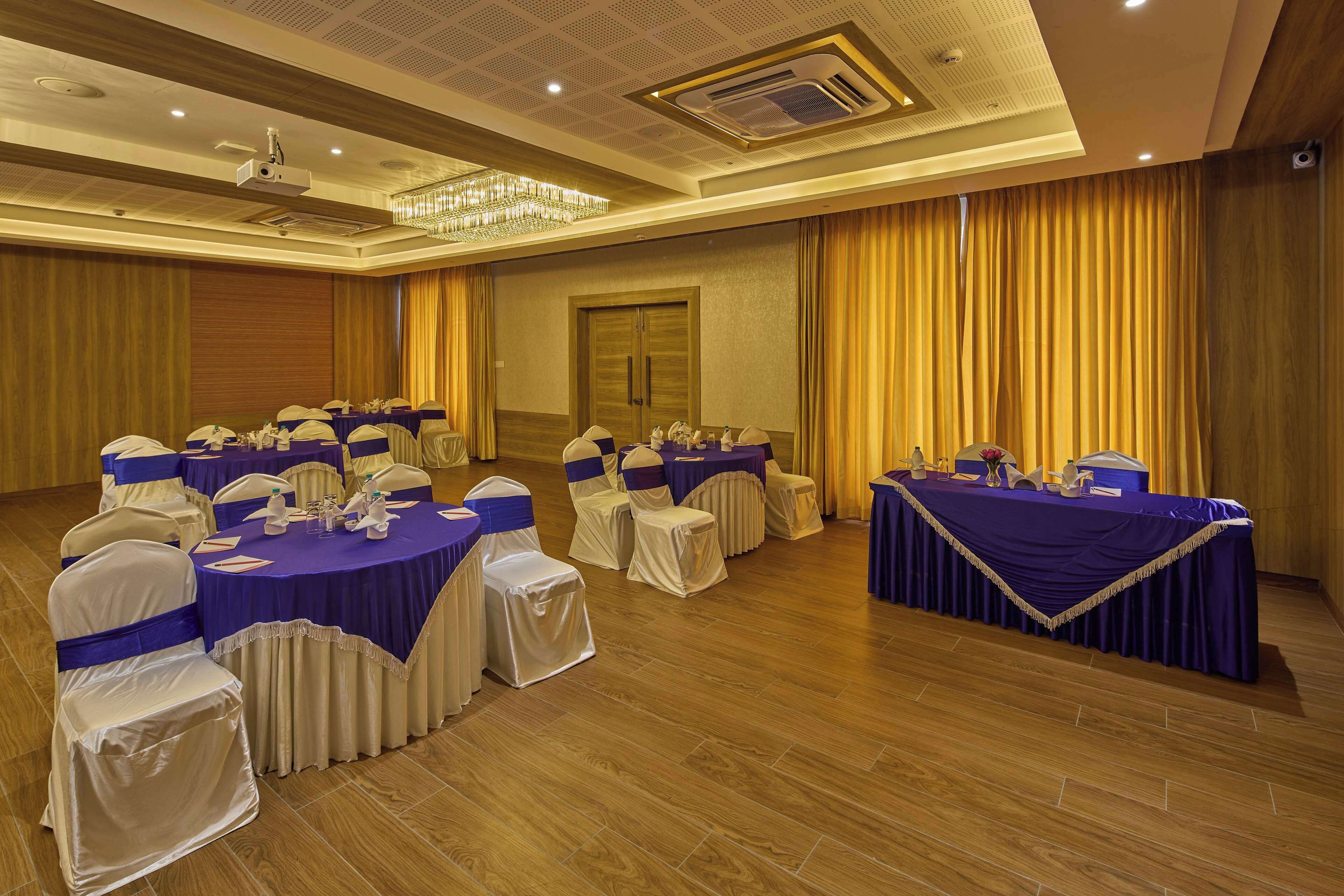 A conference room with round tables, chairs, and a stage area.