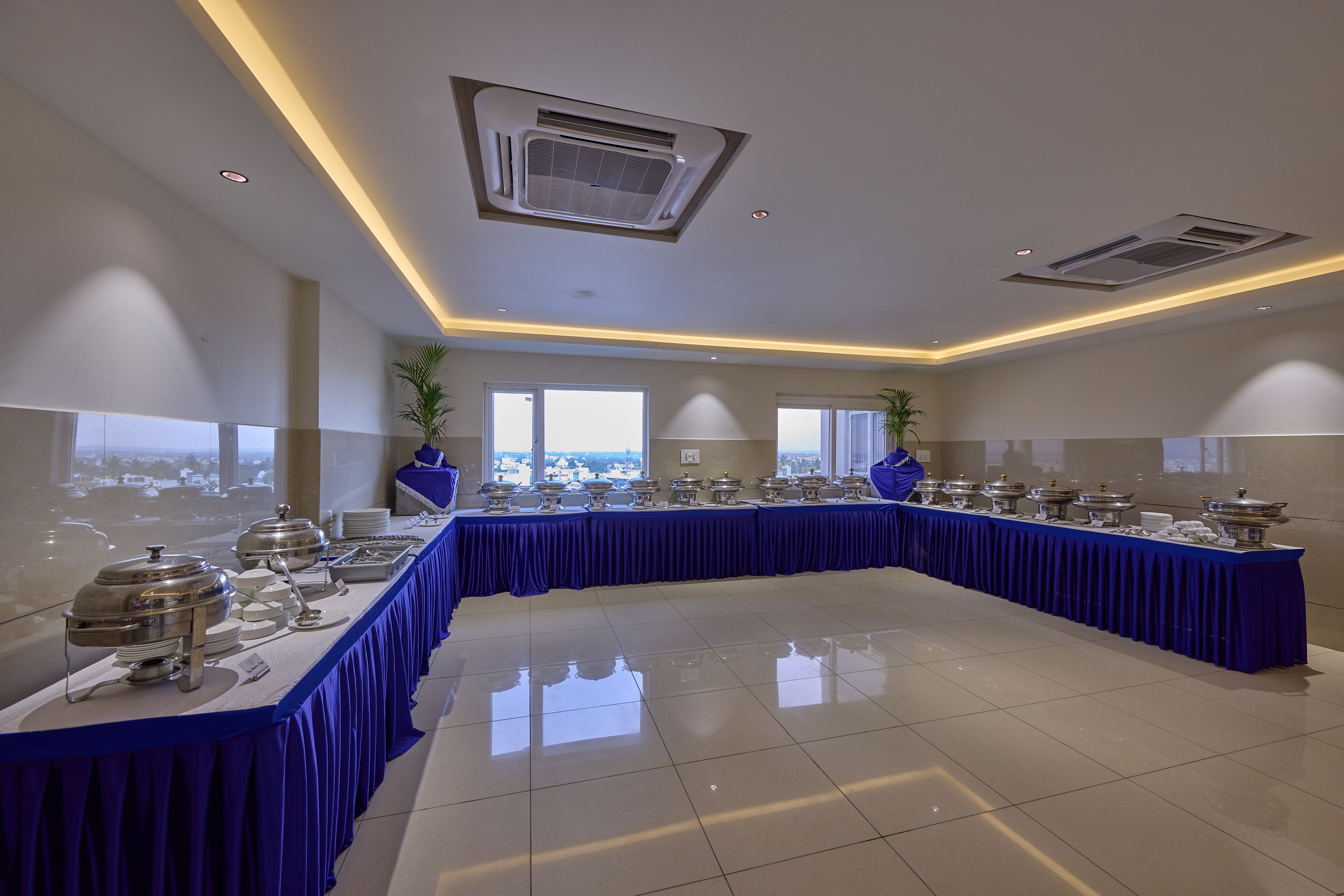 A modern conference room with a long table covered in blue, equipped with various food service items.