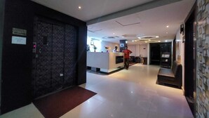 A hotel lobby with a reception desk, a guest check-in area, and a seating area. - Orbit Hotel Bagdogra (Siliguri)