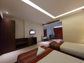 A hotel room with two beds, a desk, a TV, and a wardrobe.