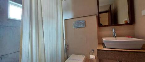 Une petite salle de bain comprenant des toilettes, un lavabo, un miroir et un rideau de douche.